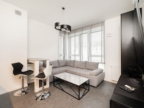A modern living room with a grey sofa, a coffee table, and a TV stand with remote controls. - Piotrkowska Modern Apartment (Łódź)