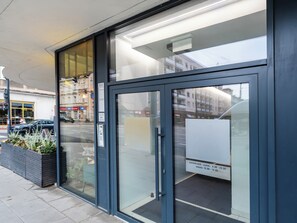 Ein moderner Gebäudeeingang mit Glasüren, Metallrahmen und einer Beschilderung, die Parkgebühren anzeigt.