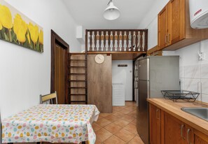A compact kitchen with a dining table, a refrigerator, and a sink. - Kazimierz Riverside Standard Apartment (Kraków)