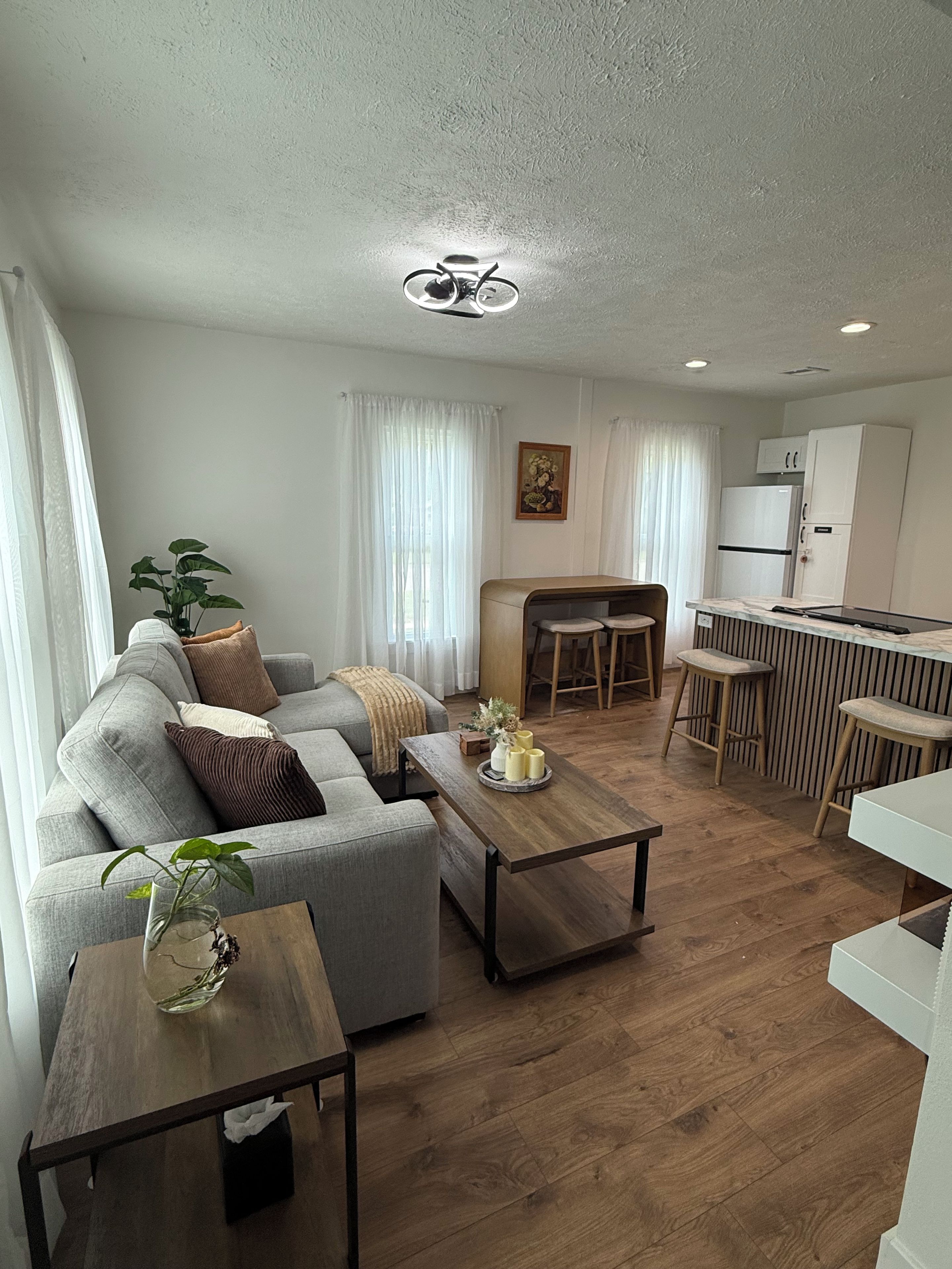 A modern living room with a sofa, coffee table, and a dining area with a bar.
