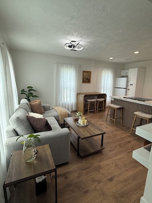 Ein modernes Wohnzimmer mit einer Couch, einem Couchtisch und einem Essbereich mit einer Bar.
