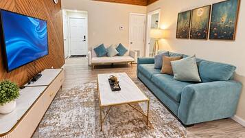 A living room with a flat-screen TV, a coffee table, a sofa, and a patterned rug.