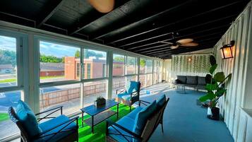 A covered outdoor seating area with wicker furniture and a green artificial turf.