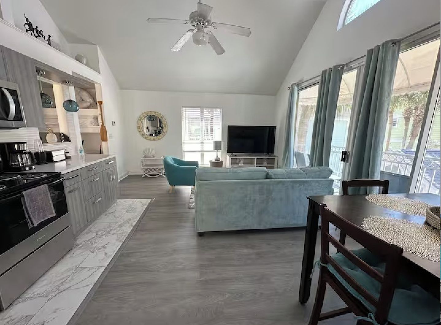 A modern living space with a kitchen, dining area, and a seating area with a television.