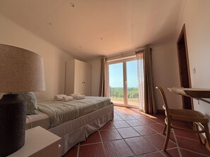 A bedroom with a bed, a desk, a chair, and a large window with curtains. - 4-bedroom house in Melides with an outdoor hot tub. (Melides)