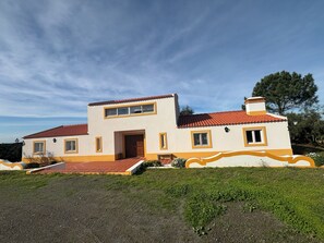 Una casa de dos pisos amb teulada de rajola vermella, entrada principal i un petit porxo.
