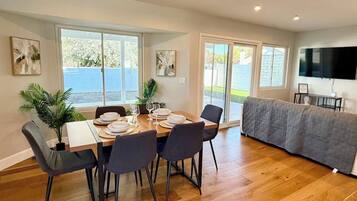 A dining area with a table set for four, a sofa, and a TV mounted on the wall.