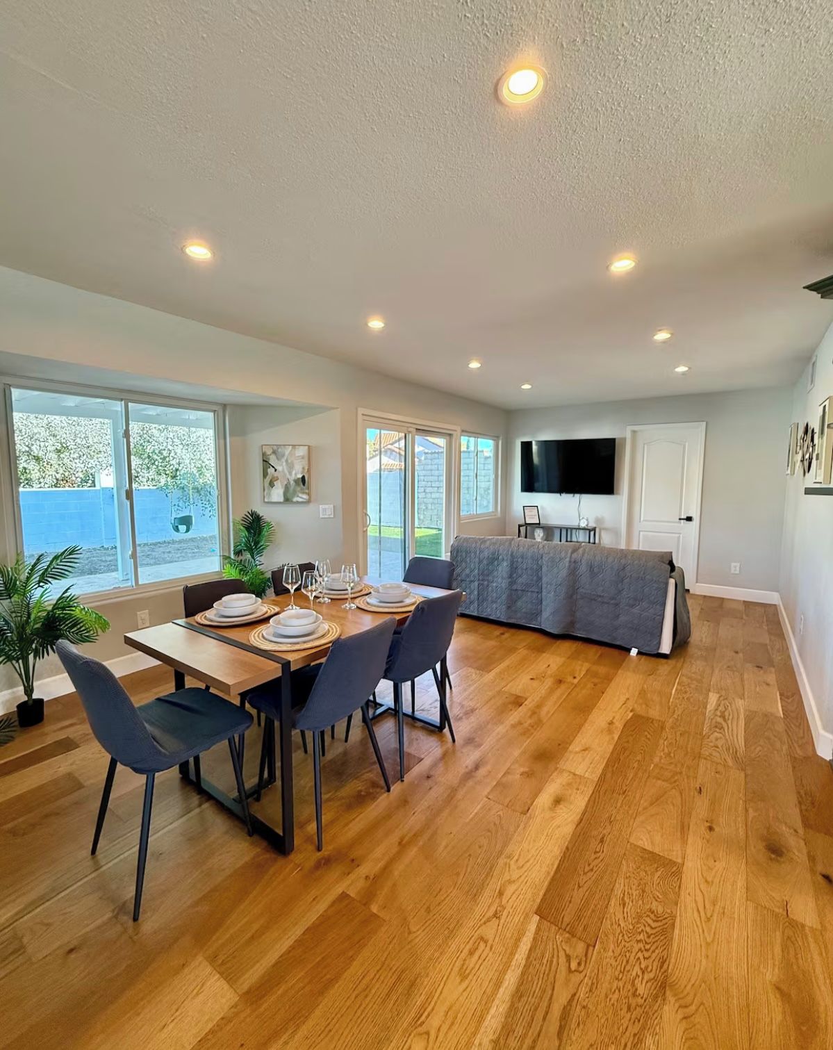 A spacious dining area with a wooden table set for six, surrounded by chairs.