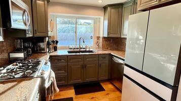A kitchen with a gas stove, microwave, sink, and a large refrigerator.
