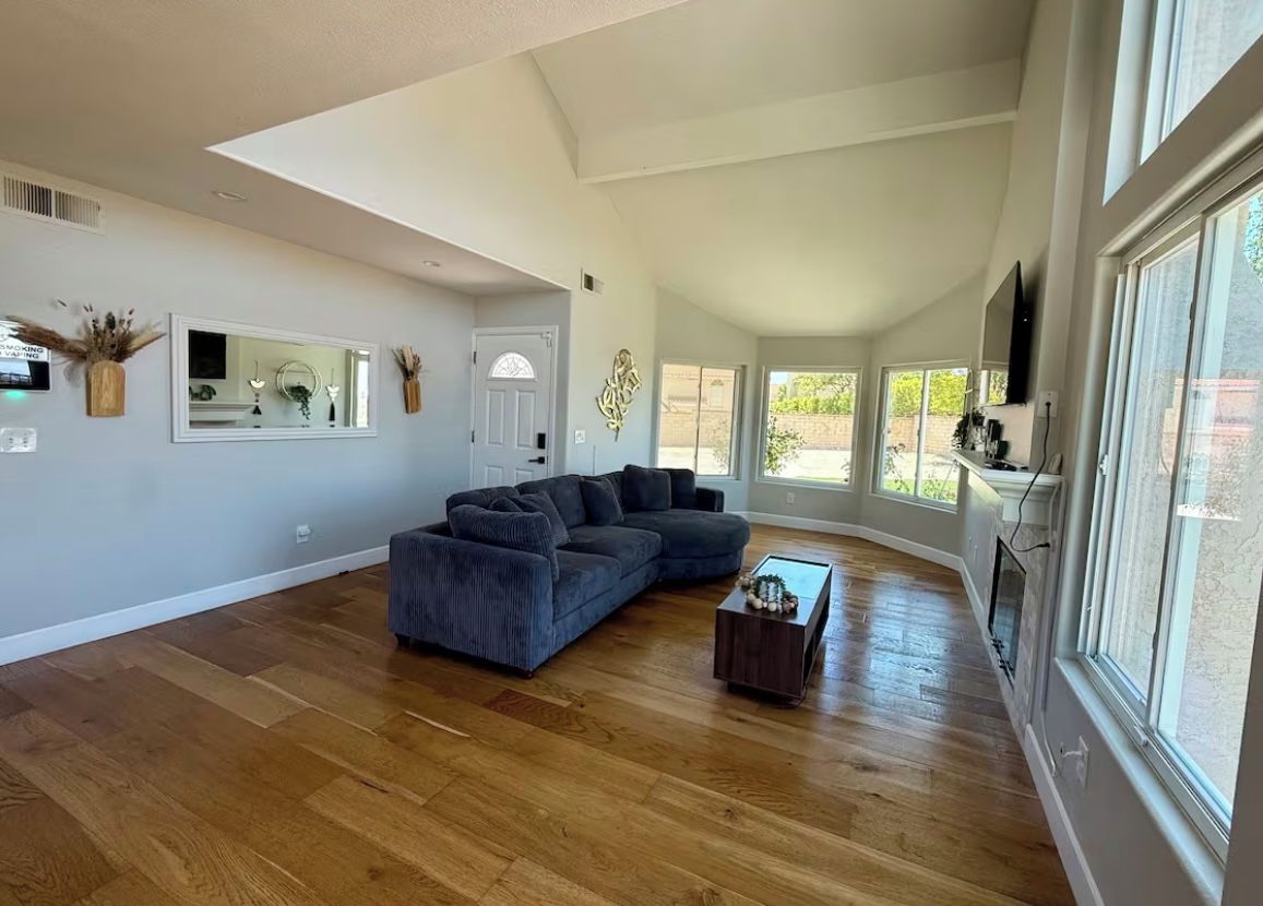 A spacious living room with a large sectional sofa, a coffee table, and a large window providing natural light.