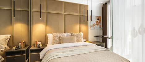 A hotel room with a large bed, bedside tables, a nightstand, a wall-mounted shelf, and a window with sheer curtains.