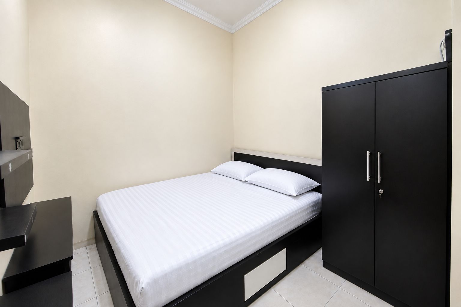 A bedroom with a bed, a wardrobe, and a desk.