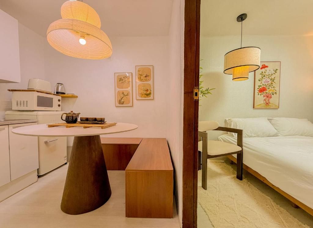 A compact hotel room with a bed, bedside table, and a dining area with a microwave.