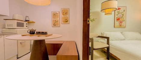 Une chambre d’hôtel compacte comprenant un lit, une table de chevet et un coin repas avec un four à micro-ondes.