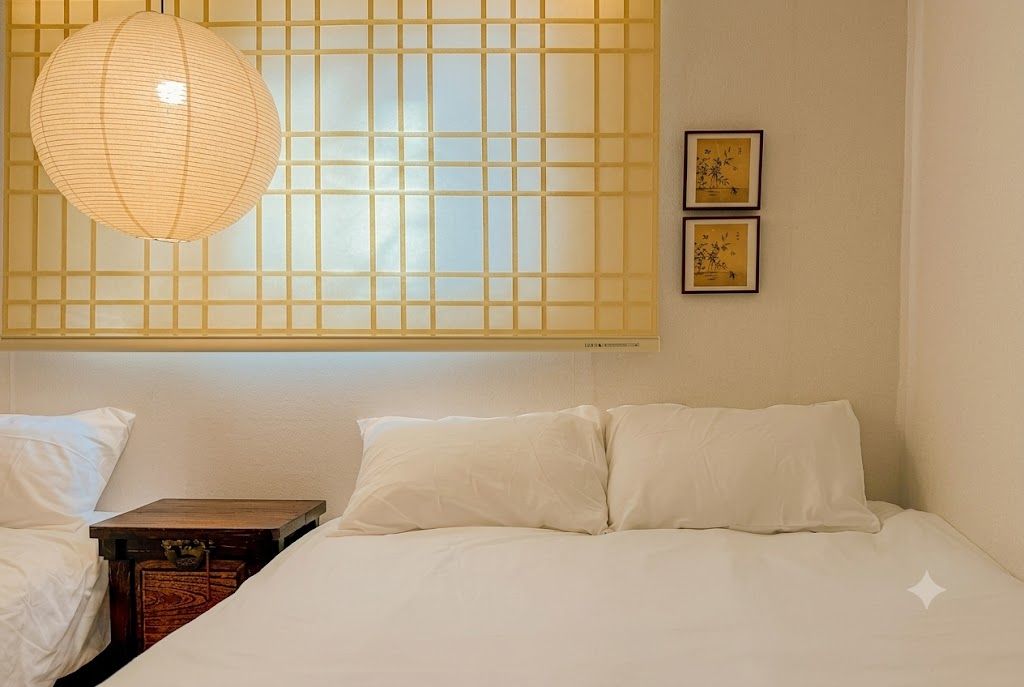 A hotel room with a bed, a nightstand, a decorative lamp, and a wall with a grid pattern and two framed pictures.