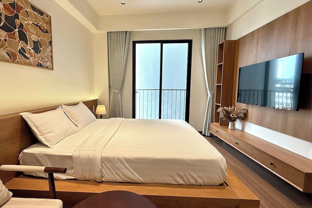 Ein Hotelzimmer mit einem Bett, einem Fernseher, einem Schreibtisch und einem Fenster mit Vorhängen.