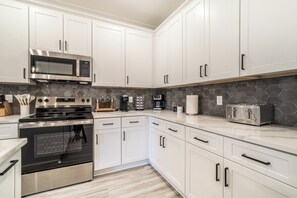 A modern kitchen with white cabinets, stainless steel appliances, and a hexagonal tile backsplash.