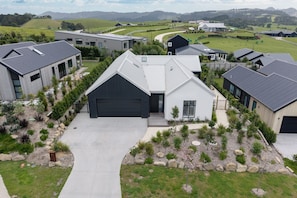 A residential area with modern houses, a driveway, and a well-maintained lawn. - Premium Matakana Getaway Close to Matakana Village (Matakana)
