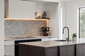 Een moderne keuken met een marmeren achterwand, een geïntegreerde vaatwasser en een strakke kraan.