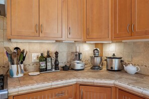 A kitchen with wooden cabinets, a countertop with various appliances, and a spice rack. - Lavish Sanctuary Main House-Hot Tub Copake Lake (Craryville)