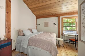 A bedroom with a bed, a desk, and a chair. There is a window with a view of greenery. - Lavish Sanctuary Main House-Hot Tub Copake Lake (Craryville)