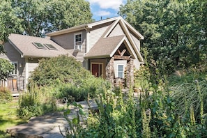 A house with a gabled roof, a front porch with stone pillars, and a small window. - Lavish Sanctuary Main House-Hot Tub Copake Lake (Craryville)