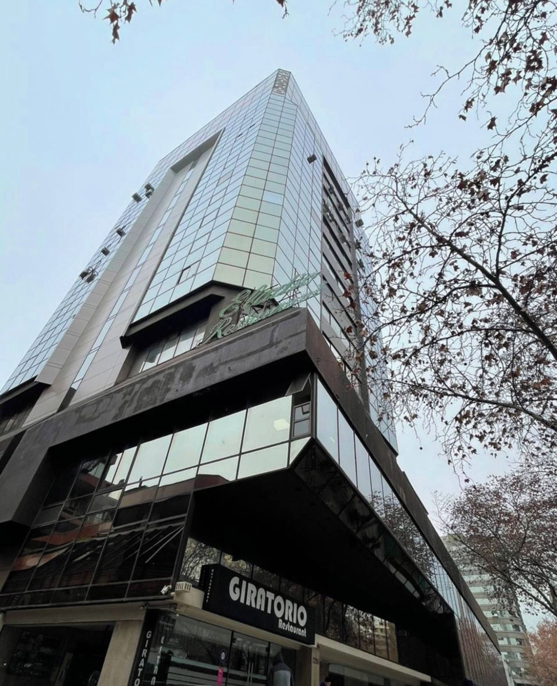 Un immeuble moderne de grande hauteur, avec un restaurant renommé, le « GIRATORIA », situé au rez-de-chaussée.