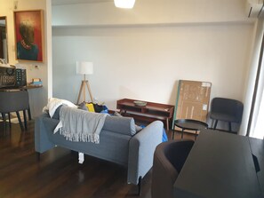 Ein Wohnzimmer mit einer Couch, einem kleinen Tisch, einer Lampe und einem Gemälde an der Wand.