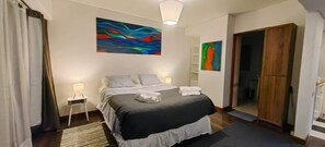 Ein Hotelzimmer mit einem Bett, einem Nachttisch, einer Lampe und zwei abstrakten Bildern an der Wand.