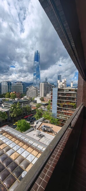 Eine Stadtansicht mit modernen Gebäuden, einem markanten Wolkenkratzer und Blick zum Himmel.