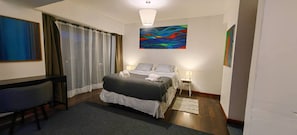 A hotel room with a bed, bedside tables, a desk, and a large abstract painting on the wall. - Terrace Studio, Costanera Views, Los Leones Metro (Providencia)