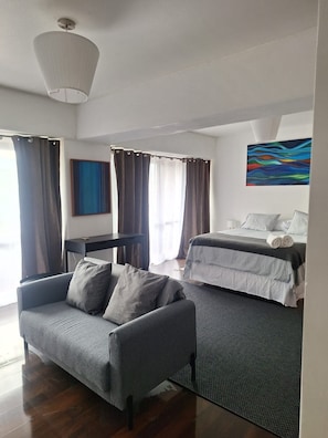 A modern hotel room with a sofa, a bed, a desk, and a painting on the wall. - Terrace Studio, Costanera Views, Los Leones Metro (Providencia)