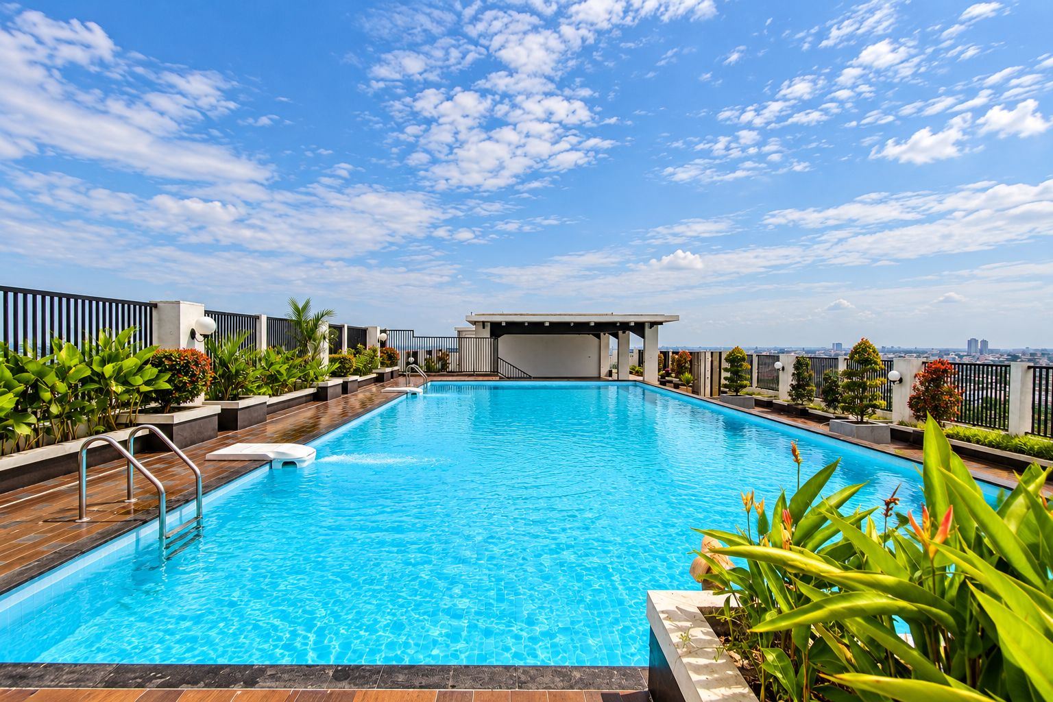 Una piscina en la azotea con vistas despejadas del horizonte urbano, rodeada de follaje y arquitectura moderna.