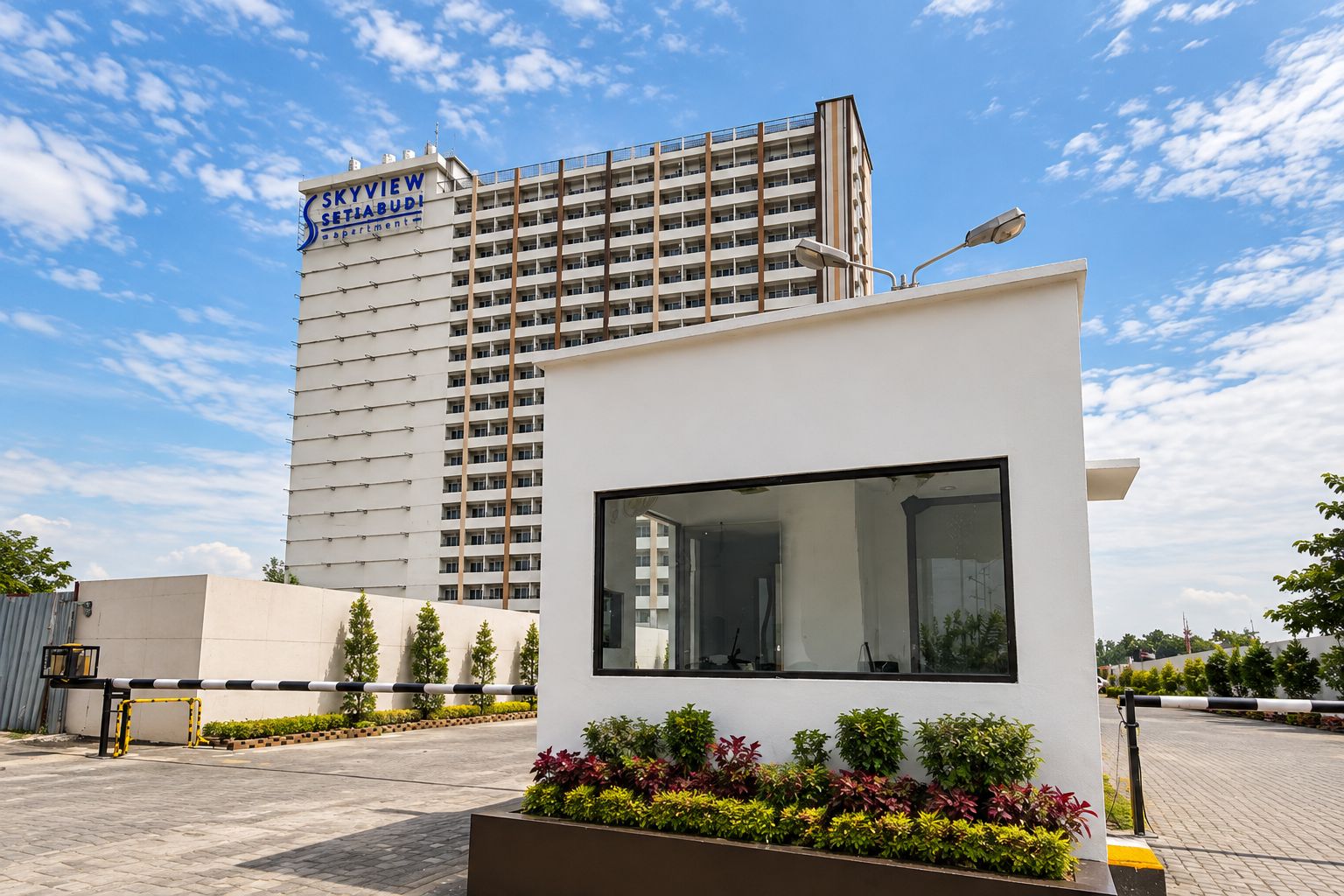 Un edificio moderno con un letrero que dice 'SKYVIEW' y una estructura más pequeña con un gran ventanal y una jardinera con diversas plantas.