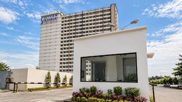 Un edificio moderno con un letrero que dice 'SKYVIEW' y una estructura más pequeña con un gran ventanal y una jardinera con diversas plantas.