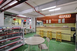 A coffee shop interior with a counter, stools, and shelves stocked with products. - Collection O Dassa (Medan)