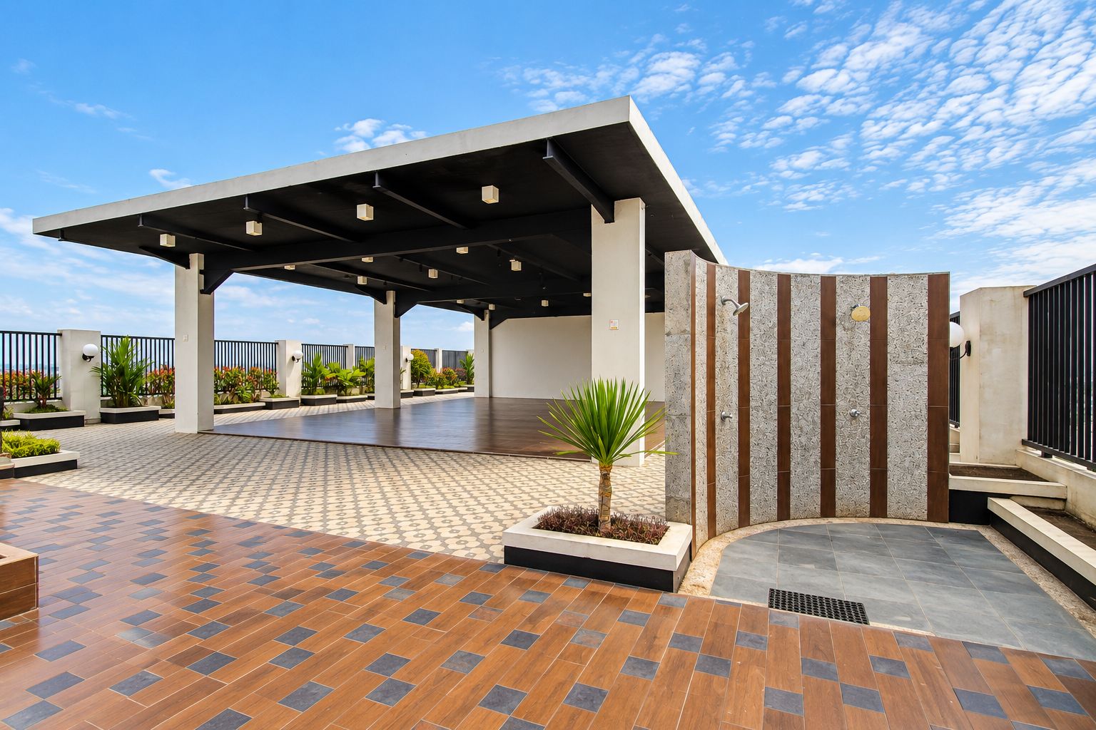 Un espacio al aire libre cubierto con piso de baldosas, una palmera y un edificio moderno con techo inclinado.
