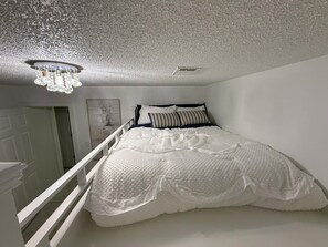 A bedroom with a white bed, a white railing, and a ceiling with a textured finish. - Spacious 1 acre property with a 6 bedrooms house in charming Brunswick with AC. (Brunswick)