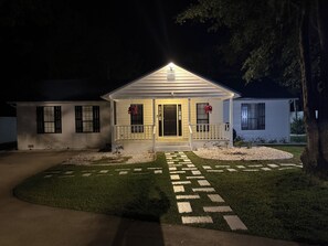 Een tweelaags huis met een veranda, een verzorgd gazon en een pad dat naar de ingang leidt.