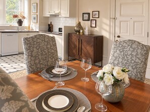 A dining area with a wooden table set for four, surrounded by patterned chairs. - OGB Heritage Loft CBD | Pool, Spa, Gym + Parking (Christchurch)