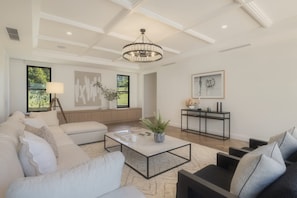 A modern living room with a sectional sofa, a coffee table, and a side table with decorative items. - The Pines Estate, Tallebudgera Valley (Tallebudgera Valley)