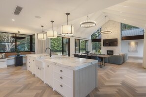 Een moderne keuken met een groot eiland, hanglampen en een open haard.