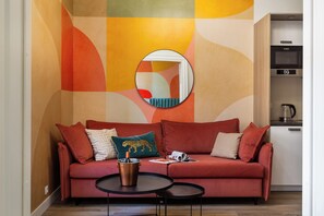 A modern living room with a red sofa, a round mirror, and a small coffee table. - Pistacchio Apartment by Fragola (Kraków)