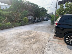 A paved road with a parked car and motorcycles. - Townhouse Oak D'Lima Hotel Sunset Road (Legian)