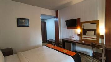 Une chambre d’hôtel comprenant un lit, un bureau, une chaise, une télévision et un miroir.