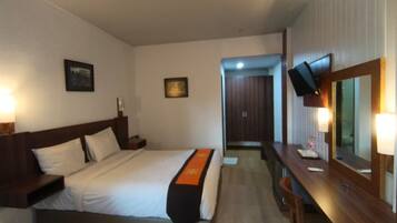 Una habitación de hotel con cama, mesita de noche, lámpara y espejo.