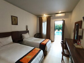 A hotel room with two beds, a desk, and a view of the outdoors. - Townhouse Oak D'Lima Hotel Sunset Road (Legian)