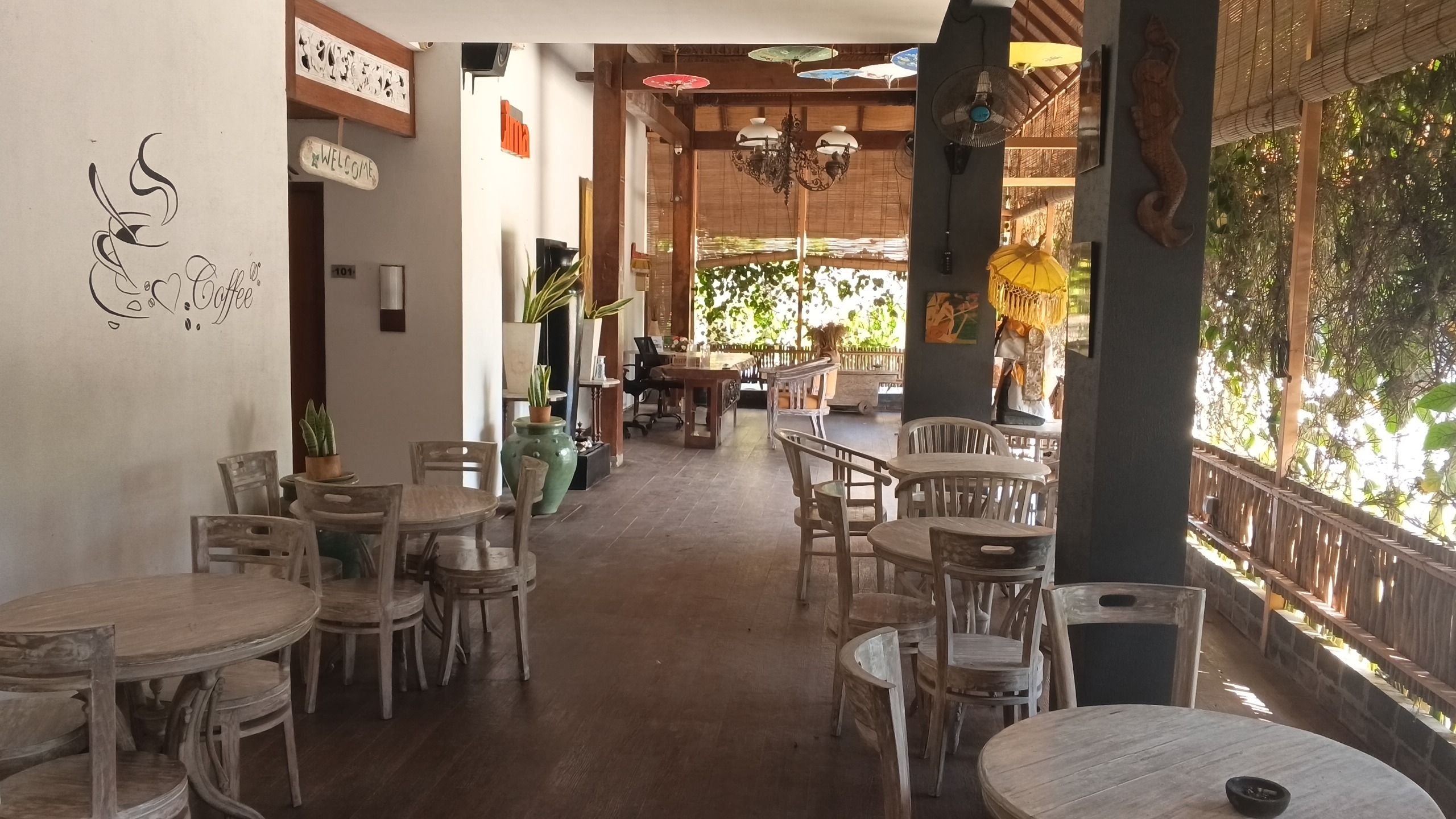 Un restaurante con mesas y sillas de madera, un letrero que dice 'Welcome' y un letrero que indica 'Coffee'.