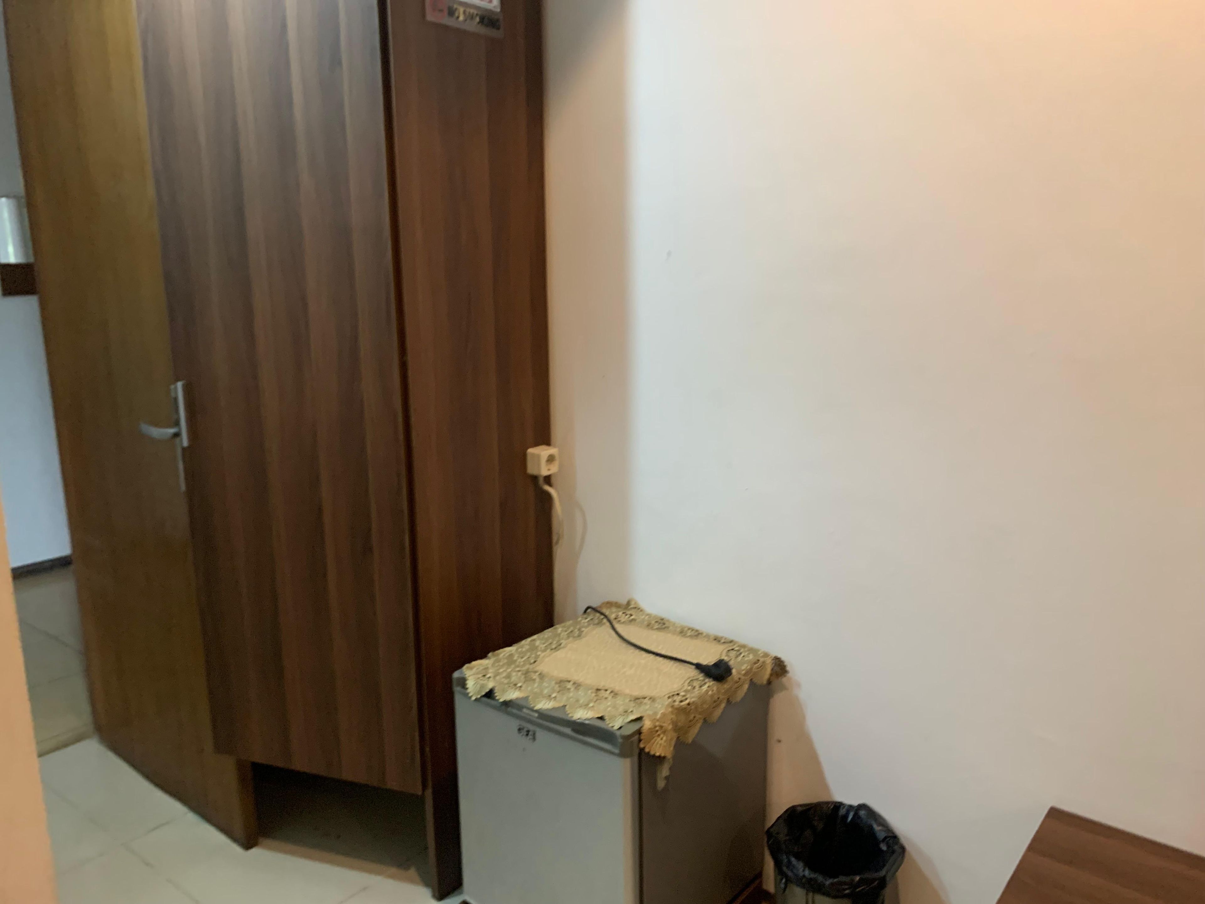 Una habitació amb una porta de fusta, una taula petita amb un teixit estampat i un gresol negre.