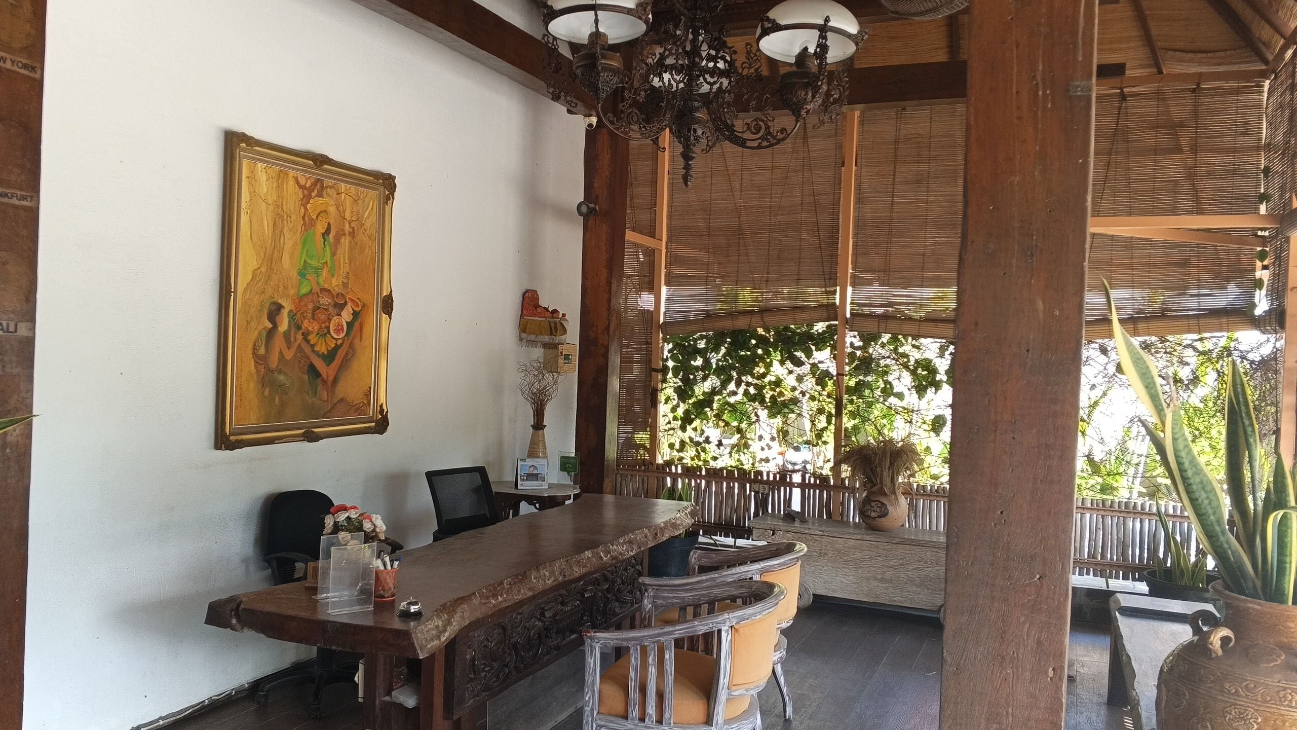 A wooden dining area with a table and chairs, a painting on the wall, and a ceiling with hanging lights.